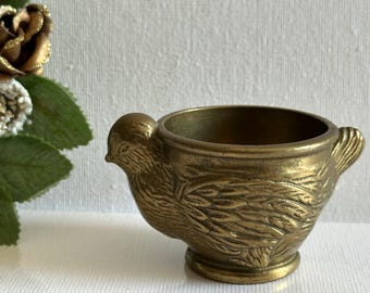 May include: A vintage brass bird-shaped container. The container is detailed with etched feathers and a small handle. The bird has a round body and a small, detailed head. The container is a warm, antique gold color.