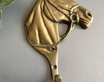 Vintage brass flat hook in the shape of a horse's head for wall mounting
