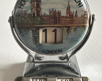 Pode incluir: Calendário de secretária cromado vintage com um design circular com a imagem do Parlamento. A data é "11" com "Londres" abaixo. O dia é "SEX" e o mês é "SET".
