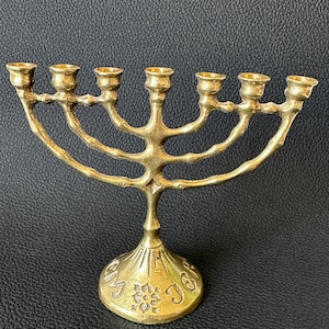 Peut inclure: Une menorah dorée avec sept bougeoirs, un design incurvé et une base inscrite "My Joy".