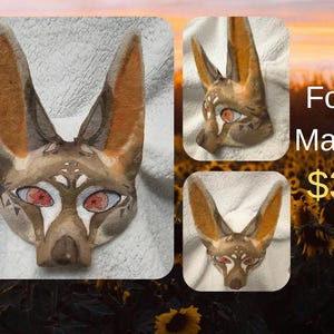 May include: A fox mask with a watercolor design. The mask features a brown and tan color scheme with orange ears and red eyes. The text "Fox Mask" is visible in the image.