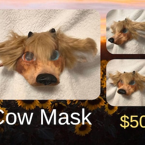 May include: A cow mask with a brown and tan face, black horns, and long, light brown fur. The mask has blue and orange eyes and a black nose. The text "Cow Mask" is displayed in white.