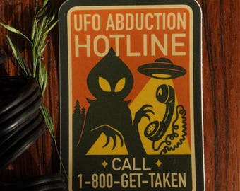 May include: A rectangular sticker with a retro design. The sticker features an orange background with the text "UFO ABDUCTION HOTLINE" in white. Below is a black alien silhouette, a UFO, and a phone. The text "CALL 1-800-GET-TAKEN" is also included.