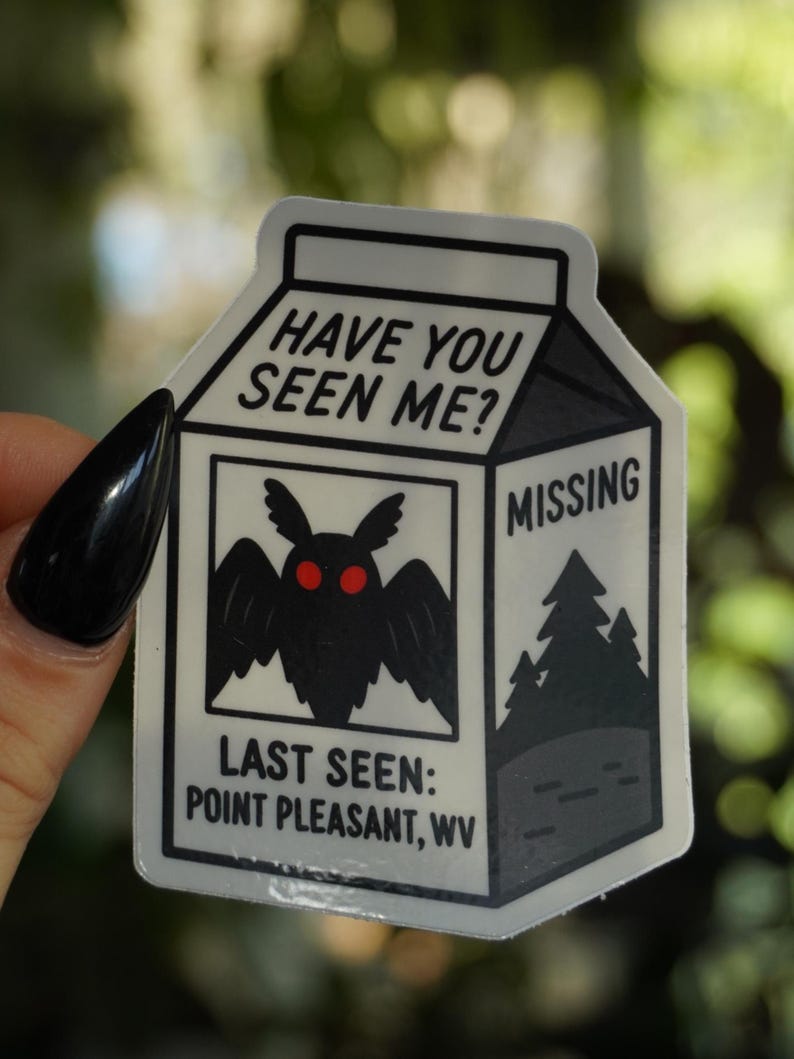 May include: A white sticker in the shape of a milk carton with the text "HAVE YOU SEEN ME?" at the top. The sticker features a black moth with red eyes and the word "MISSING". The text "LAST SEEN: POINT PLEASANT, WV" is also included.