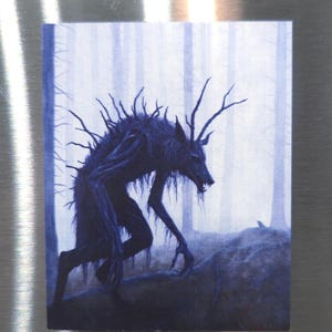 Puede incluir: Una criatura oscura y azul, con ramas que le salen del cuerpo, camina por un bosque brumoso. La criatura tiene una cabeza de lobo y garras afiladas.