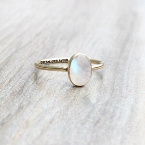 May include: A gold ring with a white oval moonstone. The ring is simple and elegant.