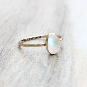 May include: A gold ring with a white oval moonstone. The ring is simple and elegant.