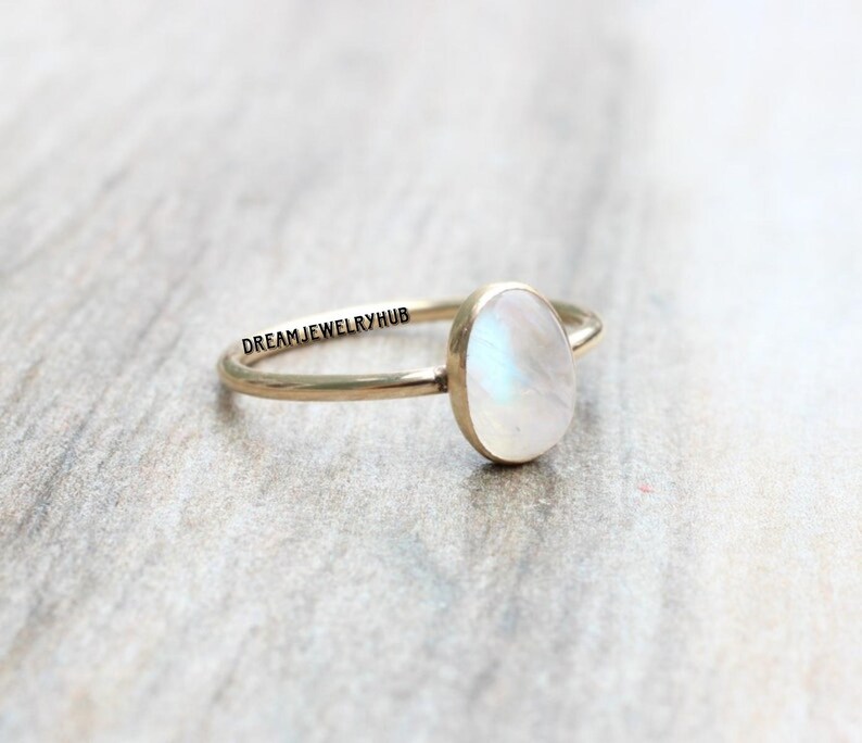 May include: A gold ring with a white oval moonstone. The ring is simple and elegant.