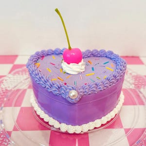 Schmuckschatulle mit Zuckerguss, Streuseln, Schlagsahne und einer rosa Kirsche