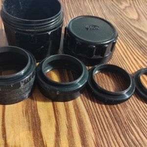 May include: A set of five black camera lens adapters. The adapters are made of metal and have a threaded design.