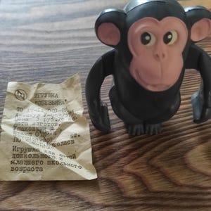 Puede incluir: Un mono de juguete negro y rosa con una etiqueta que dice "ИГРУШКА "ОБЕЗЬЯНА"  TO 17-11-003-82  Артикул У-005/371  Цена 3 руб. 70 коп.  Дата изготов.  Упаковщик  Игрушка для детей дошкольного и младшего школьного возраста"