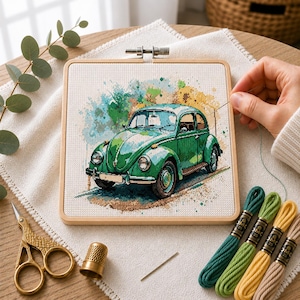 Peut inclure: Un tambour à broder carré en bois contenant un projet de point de croix représentant une voiture vintage verte. Le motif présente des éclaboussures de style aquarelle en bleu, vert et jaune. À côté se trouvent des ciseaux dorés, un dé, une aiguille et du fil.