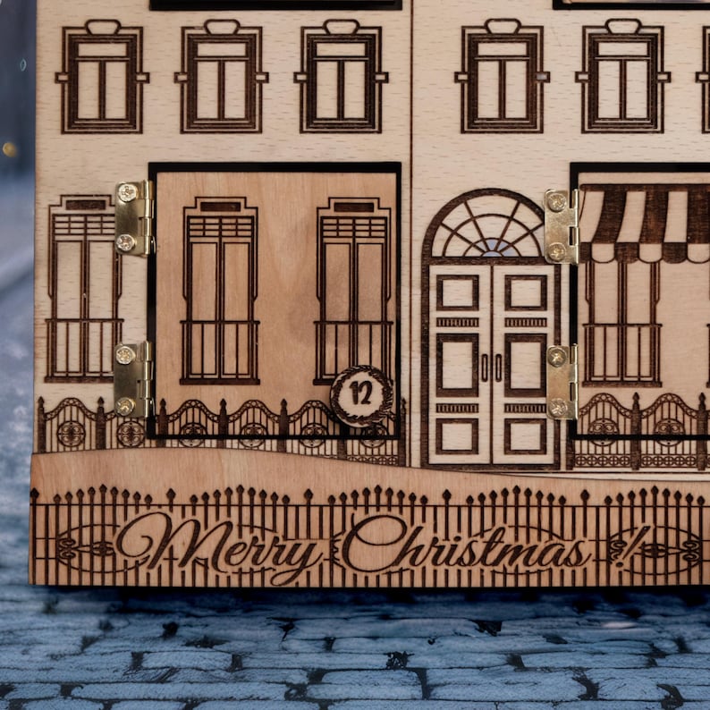 Op de afbeelding: Houten kerst adventskalender met lasergesneden huisontwerp. Voorzien van deuren, ramen en de tekst "Merry Christmas!". Inclusief een kleine deur met nummer 12. De kalender is gemaakt van lichtbruin hout.