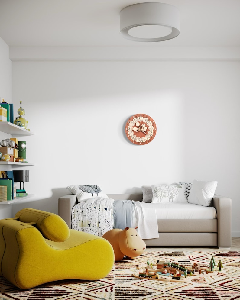 Puede incluir: Una habitaci&oacute;n infantil con un reloj de pared redondo con un dise&ntilde;o floral, un sill&oacute;n amarillo, un juguete con forma de hipop&oacute;tamo y un juego de trenes de madera sobre una alfombra estampada. Un sof&aacute; cama est&aacute; en el fondo.