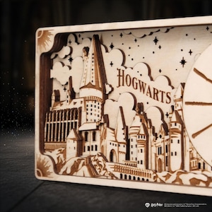 May include: Wooden Hogwarts castle wall art. The multi-layered design features the Hogwarts castle, clouds, stars, and the word "Hogwarts". The art piece is made of light-colored wood with intricate details and a sun design.