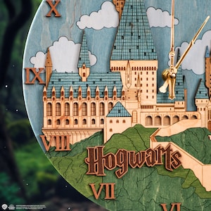 May include: A wooden clock featuring a detailed illustration of Hogwarts castle with a blue and green colour scheme. The clock face has Roman numerals and gold hands. The words "Hogwarts" are printed in brown on the clock face.