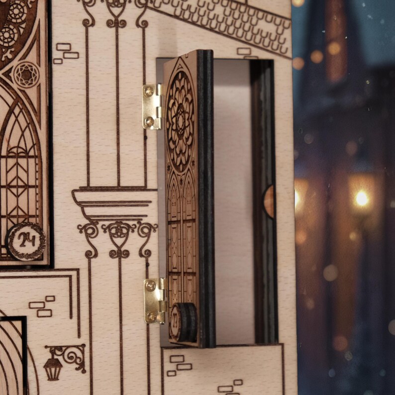 Op de afbeelding: Een houten adventskalender met een open deur die een compartiment onthult. De kalender heeft ingewikkelde lasergesneden ontwerpen van architecturale elementen, waaronder boogvensters en decoratieve kolommen. De deur is bevestigd met messing scharnieren.