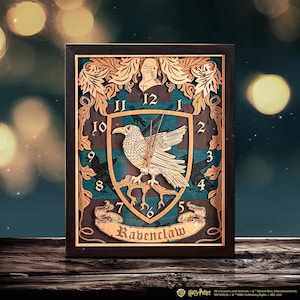 Può includere: Un orologio da parete in legno con lo stemma della casa Ravenclaw della serie Harry Potter. Il quadrante dell'orologio è uno scudo blu e verde con un corvo bianco appollaiato su un ramo. I numeri sono in nero e le parole "Ravenclaw" sono stampate in oro sotto lo scudo.