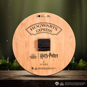 Puede incluir: Un reloj redondo de madera con el logotipo de Hogwarts Express, el texto Harry Potter y el logotipo de Wizarding World. El reloj est&aacute; hecho de madera y tiene una esfera negra.