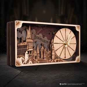 May include: A rectangular wooden desk clock featuring a layered, laser-cut depiction of Hogwarts castle. The clock face is circular with thin wooden markers and gold-coloured hands. The word HOGWARTS is engraved in the centre.