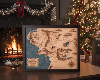 Op de afbeelding: Houten kaart van Midden-aarde met donkere lijst. De kaart toont gedetailleerde geografische kenmerken, waaronder bergen, rivieren en kustlijnen, met een blauwe oceaan en een windroos. De woorden "Middle Earth" zijn zichtbaar.