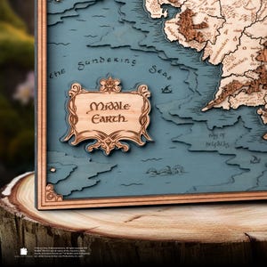 Può includere: Una mappa in legno della Terra di Mezzo, con un rilievo dettagliato della terra e del mare. La mappa è incorniciata in legno scuro e ha uno sfondo blu. Le parole "Middle Earth" sono incise su una targa di legno.