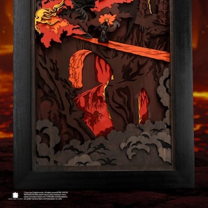 May include: A framed, layered paper art piece depicting a fiery landscape with a dark figure on a bridge. The artwork features shades of red, orange, and brown, with a black frame. The scene evokes a sense of fantasy and adventure.