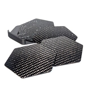 May include: A set of six black hexagonal coasters with a carbon fiber pattern. The coasters are stacked on top of each other.