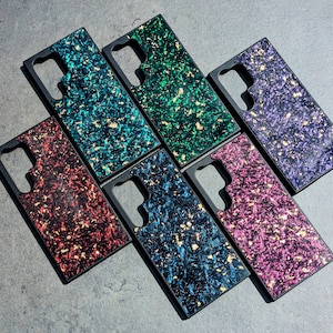 Puede incluir: Seis fundas para teléfono con diferentes patrones y colores. Las fundas están hechas de un material negro con un diseño claro y texturizado. Los patrones incluyen verde, azul, morado, rojo y rosa.