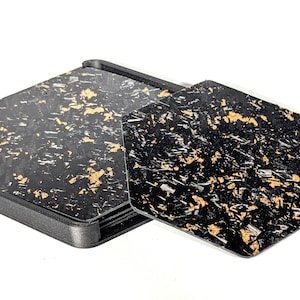 May include: A set of six black and gold hexagonal coasters with a geometric pattern. The coasters are made of a composite material and are designed to protect surfaces from scratches and heat.