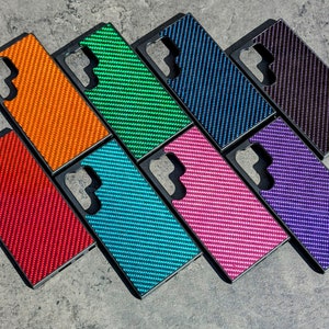 May include: Nine phone cases in different colors and patterns. The cases are made of a textured material and have a cutout for the camera lens. The colors include orange, green, blue, black, purple, red, pink, and turquoise.