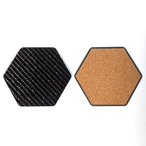 May include: Two hexagonal coasters, one with a black carbon fiber pattern and the other with a brown cork surface.