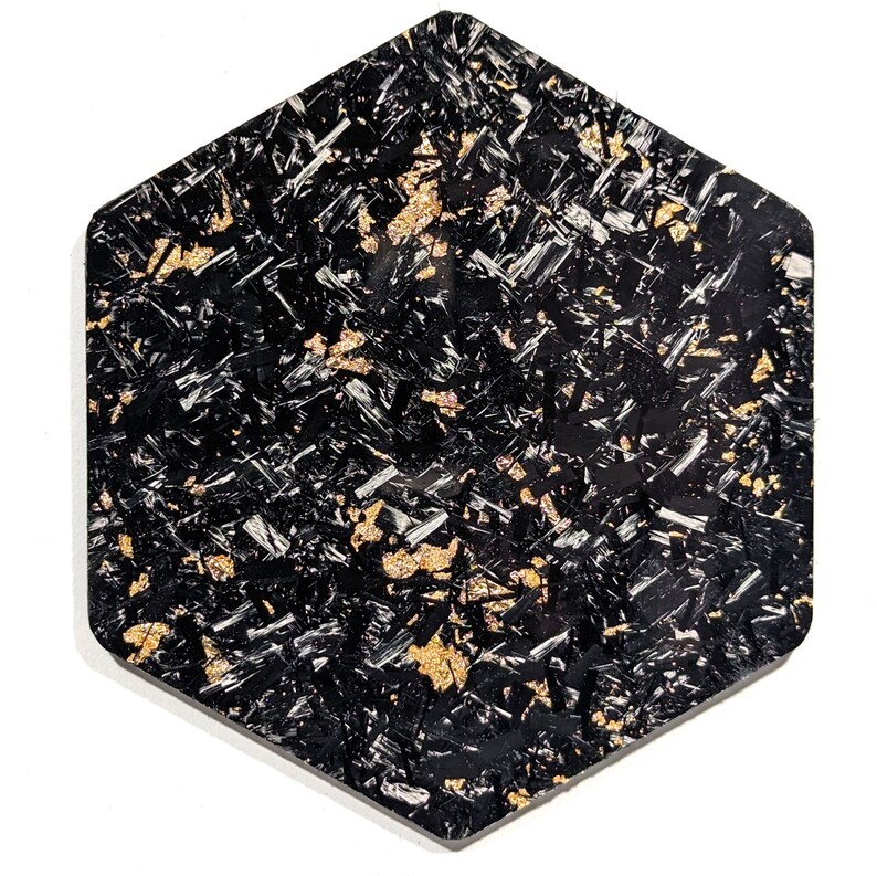 May include: Black hexagonal wall art with a textured surface and gold flecks throughout.