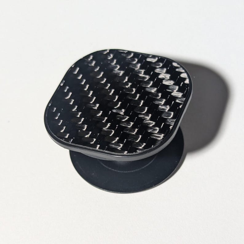 May include: A black phone grip with a carbon fiber pattern.
