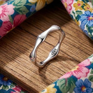 May include: A handmade wooden sign displaying the word "Welcome" in a whimsical font. It has a distressed white background and a dark brown frame, suitable for a front door or hallway.