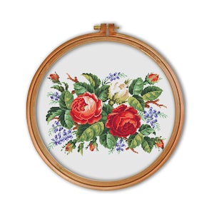May include: A cross-stitch embroidery of a bouquet of red and white roses with green leaves and purple flowers in a wooden embroidery hoop.