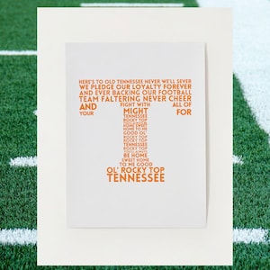 May include: A white poster with orange text that reads "Here's to old Tennessee never we'll sever we pledge our loyalty forever and ever backing our football team faltering never cheer and your fight with might Tennessee rocky top home sweet home to me good ol' rocky top rocky top top Tennessee rocky top rocky top you'll always be home sweet home to me good ol' rocky top Tennessee all of for".