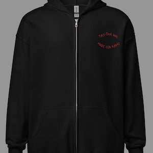 May include: Black zip-up hoodie with a hood and front pockets. The red text "THIS FACE WAS MADE FOR RADIO" is arched across the upper chest. The hoodie has a silver zipper and a tag that reads "GILDAN".