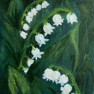 以下が含まれることがあります： 濃い緑色の背景に、白い鈴蘭の花と緑の葉を描いた絵画です。