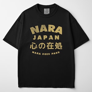 May include: Black t-shirt with a distressed gold graphic. The graphic includes the text "NARA JAPAN" in a bold font, Japanese characters, and "NARA DEER PARK". The shirt is a Comfort Colors XL-TG.
