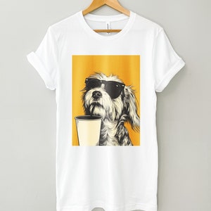 May include: White t-shirt with a graphic of a dog wearing sunglasses and holding a cup of coffee. The dog is on a yellow background.
