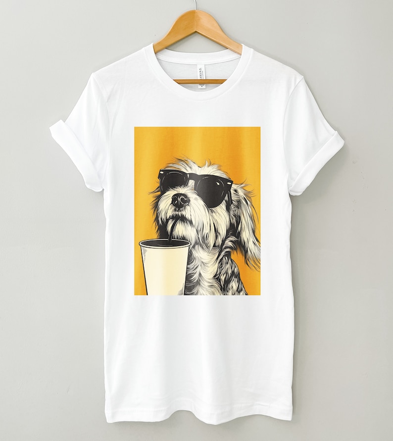 May include: White t-shirt with a graphic of a dog wearing sunglasses and holding a cup of coffee. The dog is on a yellow background.