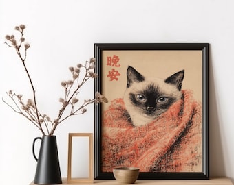 May include: A framed print of a Siamese cat wearing a red scarf. The print is on a beige background with the Japanese characters "暖炉" in red. The print is framed in black and is sitting on a wooden table with a small wooden frame and a brown bowl.