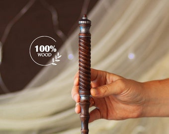 May include: A brown wooden wand with silver accents and a twisted design. The wand is 100% wood and is held in a hand.