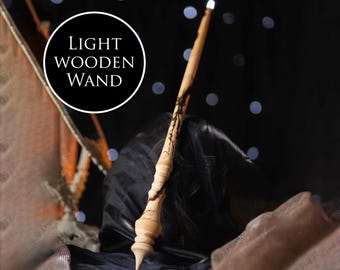 May include: A light wooden wand with a black and white design. The wand is lit up at the tip and is resting on a black fabric surface.