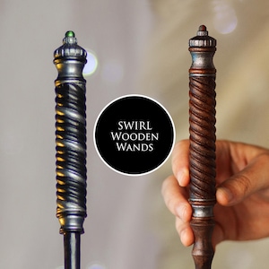 May include: Two wooden wands with a swirl design. One wand is silver with a green gem, the other is brown with a red gem. The wands have a detailed, carved spiral pattern. The text "SWIRL WOODEN WANDS" is in a black circle.