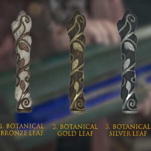 May include: Three decorative wooden finials with a leaf design. The finials are painted in bronze, gold, and silver.
