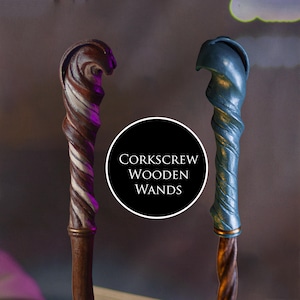 Op de afbeelding: Twee houten kurkentrekkers met wervelende ontwerpen. Eén toverstaf is bruin met witte en bruine strepen, de andere is blauw met een metallic afwerking. De toverstaven hebben een decoratief handvat en de tekst "Corkscrew Wooden Wands".