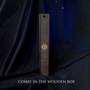 May include: A tall, dark wooden box with a decorative geometric design. The box is rectangular and has a lid. The text "COMES IN THE WOODEN BOX" is at the bottom of the image.