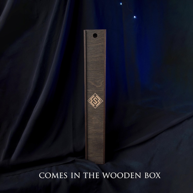 May include: A tall, dark wooden box with a decorative geometric design. The box is rectangular and has a lid. The text "COMES IN THE WOODEN BOX" is at the bottom of the image.